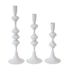 three tall white candlesticks sitting next to each other