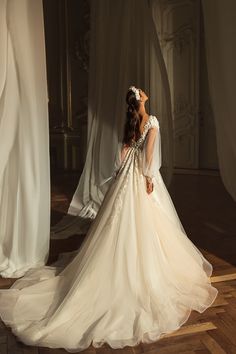 a woman in a wedding dress is standing on the floor with her back to the camera