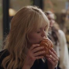 a woman is eating a pastry while standing outside