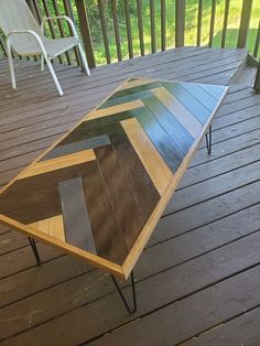 a coffee table made out of plywood and metal on a deck with chairs in the background