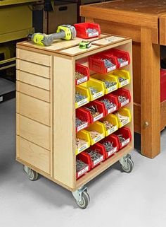 a workbench with drawers and bins on wheels in front of a desk