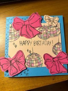 a happy birthday card with pink bows on it and a globe in the background, sitting on a table