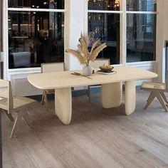 a dining room table and chairs in front of large windows