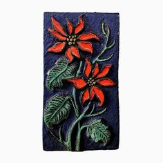 a ceramic tile with red flowers and green leaves