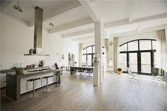 an open kitchen and living room area in a large apartment with wood floors, white walls, and high ceilings