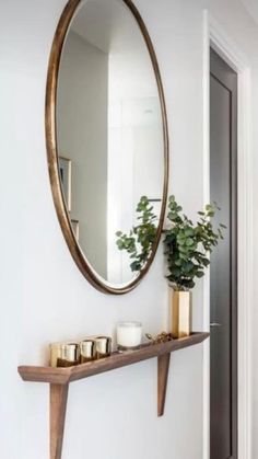 a mirror and some candles on a shelf in a room with white walls, wood floors and wooden flooring