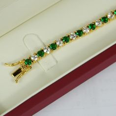 YELLOW GOLD FINISH Created Diamond Round Cut Green Emerald Tennis Bracelet  This green emerald and created diamond bracelet is made in the style of a tennis bracelet with a circular fine finish, with created green emerald gems. It is a bracelet sure to provide you with style comfort. The green emerald gems are studded with small diamanté's carved to perfection, offering a great sheen and pristine look.  Round diamonds are traditionally the first and most popular diamond that's given as a symbol of commitment. They have a classic uniform and symmetrical shape that consists of 58 facets, which qualifies them a brilliant cut. The faceting on round cut diamonds also makes colour and inclusions appear better than in other fancy shapes. In fact, these stones are so beloved that over 50% of all d Classic Bracelets With May Birthstone, Classic May Birthstone Bracelets, Luxury Green Tennis Bracelet For Formal Events, Elegant Emerald Tennis Bracelet For Wedding, Luxury Emerald Tennis Bracelet As Gift, Luxury Emerald Tennis Bracelet Gift, Elegant Yellow Gold Tennis Bracelet As Gift, Elegant Yellow Gold Tennis Bracelet Gift, Formal Round Bracelet With May Birthstone