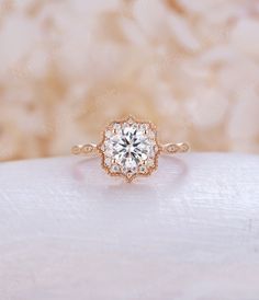 an engagement ring with a flower design on the front and side, sitting on top of a