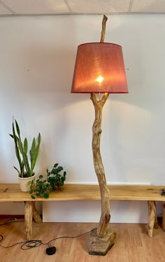 a wooden table with a lamp on it and a potted plant next to it