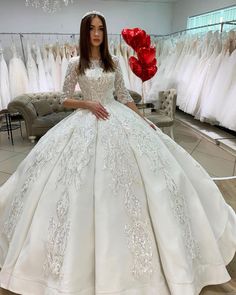 a woman in a white wedding dress is standing next to some dresses on hangers