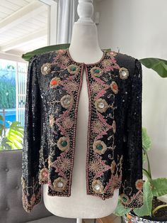 Stunning, sequin, evening jacket with heavy gold embroidery and black beading. Jacket is fully lined and has shoulder pads that could be removed with one hook and eye closure in the front. In overall excellent vintage condition with no notable flaws, no holes, snags, stains, or missing beads or sequins, however there are loose gold threads near the top of the shoulders. Tag reads Suzette International, Paris, Santa Fe, would best fit a size small. Measurements Chest 38in/96.5cm Length 20in/51cm Shoulders 15in/38cm Sleeve 23in/28cm *Please keep in mind that unless otherwise noted, all items in my shop are used or previously owned, normal wear and tear is expected, flaws that are noted are range from major to minor, things like a missing stitch here or there my not be included. *Please read Diane Freis, Evening Jacket, Womens Jackets, Evening Jackets, Patchwork Bags, Gold Embroidery, Gold Threads, Blue Suede, Little Miss