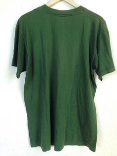 a green t - shirt hanging on a white wall