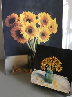 a painting of sunflowers in a blue vase on a table next to an easel