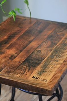 a wooden table sitting on top of a hard wood floor next to a potted plant