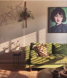 a living room with a green couch and paintings on the wall