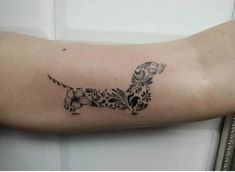 a black and white tattoo of a dog on the left arm with flowers around it