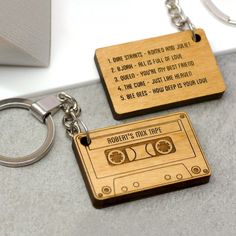 two wooden keychains with an old fashioned cassette tape design on them, one has the words robin's mix tape printed on it