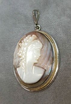 Hallmarked 800 silver Mother of Pearl cameo pendant. The cameo pendant measures approximately 1 1/2 inches x 1 inch. The necklace chain attached to the cameo pendant is sold separately. Other necklace styles are also available. The cameo pendant is in very good condition. The cameo pendant is circa 1940. The cameo pendant comes in a quality gift box. Silver Cameo Round Pendant Jewelry, Silver Cameo Jewelry With Round Pendant, Round Silver Cameo Necklace, Cameo Medallion Jewelry For Anniversary, Collectible Cameo Jewelry With Round Pendant, Cameo Medallion Necklaces For Anniversary, Collectible Cameo Round Pendant Jewelry, Silver Cameo Medallion Necklace, Silver Cameo Oval Pendant Jewelry