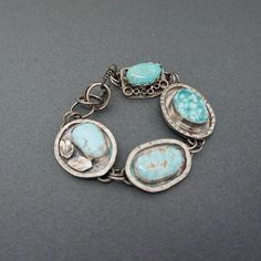 This lovely gemstone bracelet is one of a kind and a great statement piece!  Each charm link has been embellished in a very unique way to make a one of a kind bracelet. The lovely turquoise stones  are of the highest quality. I have used 2 Cloud Mine Turquoise stones with 2 Sleeping Beauty Stones. The turquoise contrasts beautifully with the oxidized sterling silver. I have added a variety of embellishments to the outside of the stones and then finished the bracelet with a handcrafted hook clasp. The bracelet is about 7" and is somewhat adjustable.  The bracelet will be sent in a linen bag, inside a gift box, ready for gift giving! *Take a closer look* 4 turquoise cabochons- Cloud Mine and Sleeping Beauty hook clasp Length-7" adjustable *Surface Features* Granulation Square wire oxidation Bohemian Sterling Silver Oval Bracelets, Oxidized Turquoise Oval Jewelry, Bohemian Oval Sterling Silver Bracelets, Unique Hand Forged Bracelet Jewelry, Sterling Silver Jewelry With Turquoise, Unique Turquoise Sterling Silver Bracelets, Handmade Turquoise Sterling Silver Bracelets, Unique Turquoise Metal Bracelet, Unique Bracelets With Natural Stones