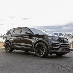 a black suv parked in front of a body of water