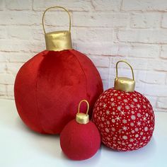 three red and gold ornaments sitting next to each other on a white counter top in front of a brick wall