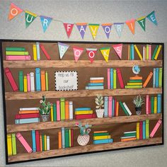 a bulletin board is decorated with colorful books and bunting garlands on the wall