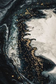 an abstract black and white painting with gold flecks on the water's surface