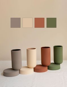 five different colored vases sitting on top of a white table next to each other