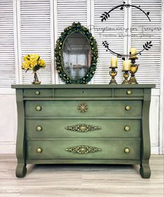 a green dresser with two candles and a mirror