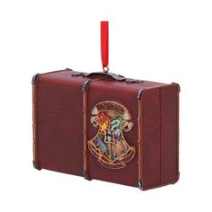 a harry potter suitcase ornament hanging from a red ribbon on a white background