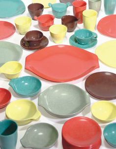 a table topped with lots of different colored plates and bowls on top of each other