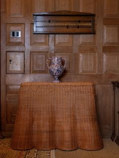 a vase sitting on top of a table in front of a wooden paneled wall