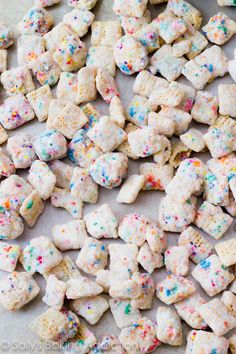 colorful sprinkles and white dog treats are on a baking sheet, ready to be eaten