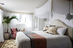 a bedroom with a white bed and hanging decorations on the wall next to a window