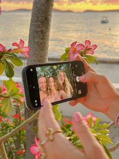 a woman taking a photo with her cell phone on the beach at sunset or sunrise