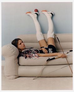 a woman laying on top of a couch with her legs crossed and holding an arrow