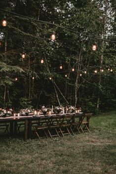 an outdoor dinner table with lights strung from the trees