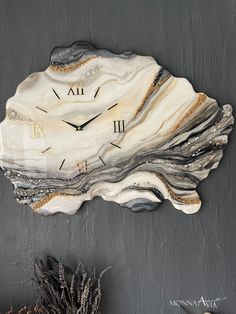 a clock made out of rock with roman numerals on the face and hands