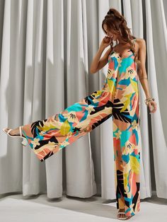 This stylish Backless All Over Print Wide Leg Cami Jumpsuit is perfect for your next warm-weather getaway. The Boho-inspired design features an all-over geometric pattern, giving it a unique and eye-catching look. The loose fit and natural waistline create an effortlessly flattering silhouette, while the soft and lightweight fabric is comfortable and breathable. The spaghetti straps and sleeveless cut give it a timeless and elegant feel. Crafted with 100% polyester, this cami is sure to keep you Tropical Printed V-neck Jumpsuits And Rompers, Multicolor Tropical Print V-neck Jumpsuits And Rompers, Beach Printed Patterned Jumpsuits And Rompers, Casual Patterned Jumpsuits And Rompers For Vacation, Beach Patterned Jumpsuits And Rompers, Tropical V-neck Printed Jumpsuits And Rompers, Printed Tropical V-neck Jumpsuits And Rompers, Chic Printed Jumpsuit For Vacation, Chic Printed Jumpsuits And Rompers For Vacation