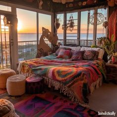 a bedroom with a bed covered in blankets and pillows next to a large window overlooking the ocean