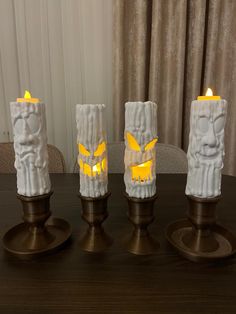 three candles with carved faces on them sitting on a table