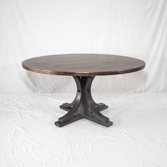 a round wooden table sitting on top of a white sheet