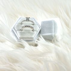 two wedding rings sitting on top of a white fur covered floor