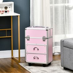 a pink suitcase sitting on top of a hard wood floor next to a gray couch