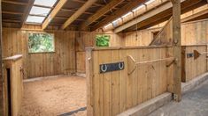 the inside of a horse barn with wooden walls and stalls on either side of it