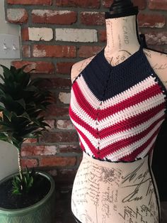 a crocheted top on a mannequin next to a potted plant