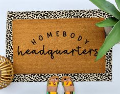 a door mat with the words homeboy headquarters written on it next to two pairs of flip flops