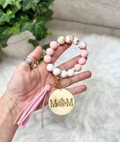 a woman's hand holding two bracelets with the word mom on it