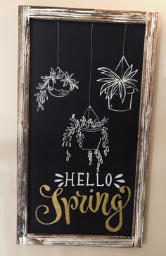 a chalkboard with the words hello spring hanging from it's sides and plants