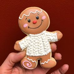 a hand holding a small ginger cookie with icing on it